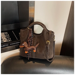 Close-up of dark brown matte suede handbag with contrast stitching and dachshund charm