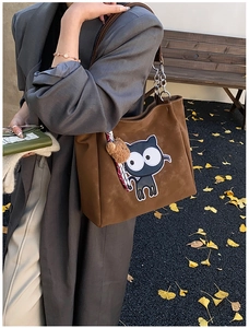 Détail du sac cabas en daim marron avec écusson chat et breloque petit ours