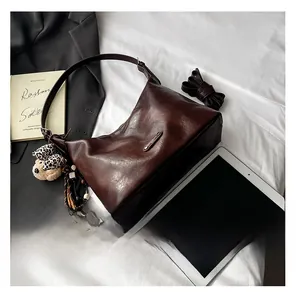 Detail of dark brown shoulder bag with leopard bear charm and interior capacity