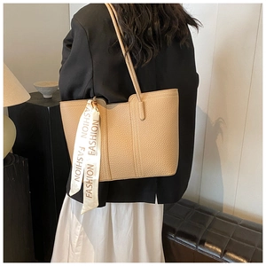 Schicke beige Tragetasche aus Leder mit dekorativem Seidenschal am Model für den Alltag