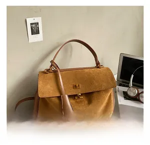 Close-up of brown suede tote with leather straps and metal twist lock in office setting