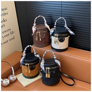 Detail of four suede bucket bags with heart scarves and lock charms on leather sofa