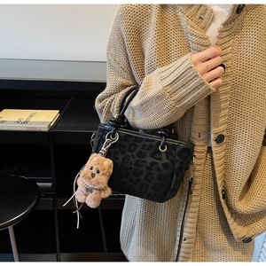 Gros plan du sac à main léopard avec ferrures dorées et breloque ours en peluche