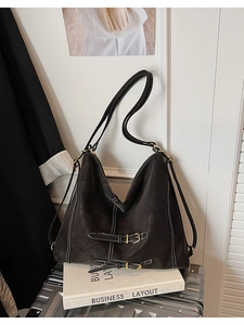 Détail du sac vintage en cuir mat avec surpiqûres blanches et sangles à boucle