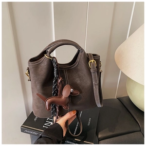 Detail view of brown matte bucket bag with white stitching and dachshund charm