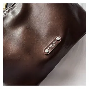 Close-up of brown pebbled faux leather bag with brand logo plaque and silver rivets