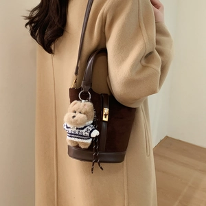 Détail du sac seau en daim marron foncé avec fermoir doré et pendentif chien en peluche