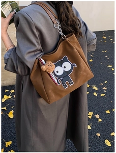 Détail d'un sac cabas marron mat avec broderie chat et pendentif ours en peluche doux