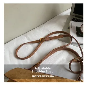 Close-up of adjustable brown suede shoulder strap with elegant gold metal buckle detail