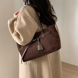 Close-up of deep brown suede tote bag featuring metallic buckle and vintage texture