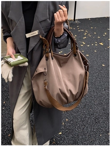 Detail of a large khaki tote bag styled with a grey trench coat on a city street