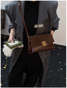 Detail of dark brown leather crossbody bag with vintage golden buckle and suede texture