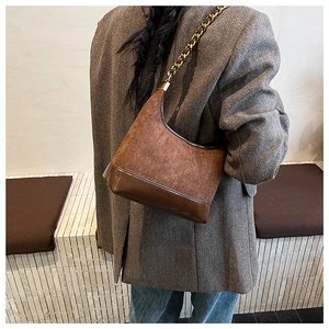 Detail of vintage brown suede shoulder bag with matte texture and chain strap on shoulder