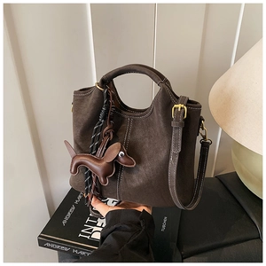 Detail of dark brown retro bucket bag with white contrast stitching and puppy charm
