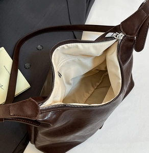 Detail view of the dark brown shoulder bag interior with fabric lining and zipper pocket