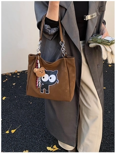 Détail du sac cabas marron avec broderie de chat noir et pendentif ours en peluche