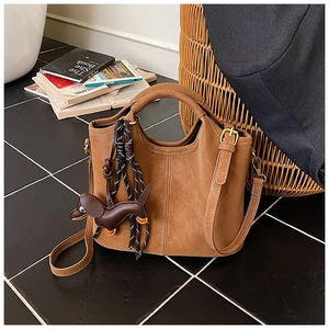 Detailed view of brown lychee leather tote with white stitching and dog charm