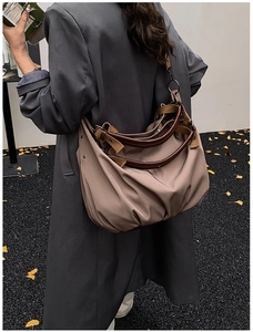 Outdoor shot of a large taupe canvas tote bag with brown leather handles and shoulder strap