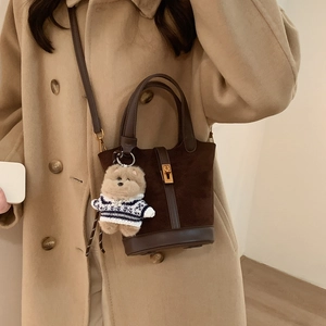 Détail du sac seau en daim avec breloque nounours sur manteau en laine camel chic