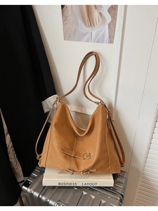 Vue détaillée du sac hobo en similicuir camel avec sangles à boucles sur une valise argentée