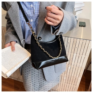 Detail showing the mixed textures of matte suede and glossy patent leather on the handbag