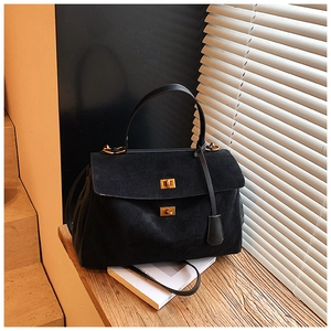Detailed view of black suede tote bag with golden twist lock on wooden stairs