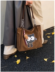 Gros plan du sac cabas en daim marron avec broderie chat et bandoulière chaîne