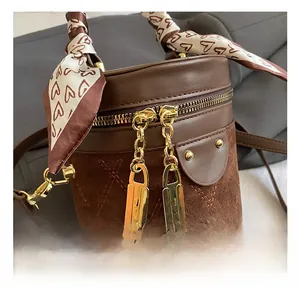 Detail of brown bucket bag showing quilted suede, gold hardware, and heart silk scarf
