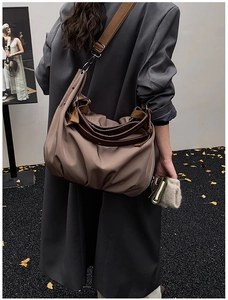 Detail of khaki large tote bag featuring wide fabric strap and dark brown top handles