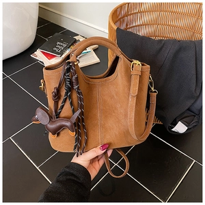 Detail of brown matte bucket bag featuring contrast stitching and dachshund charm