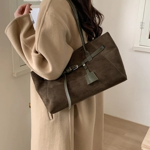 Close-up of vintage brown suede tote bag featuring contrasting green leather straps