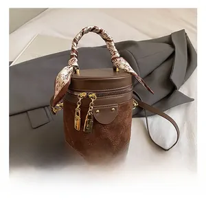 Detail of a brown bucket bag with quilted leather texture and a silk scarf wrapped handle