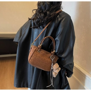 Détail du sac seau léopard avec anneaux métalliques et breloque ours sur le mannequin
