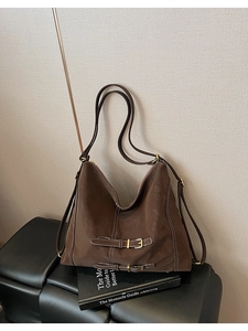 Détail d'un sac cabas marron foncé avec surpiqûres blanches et boucles dorées chic