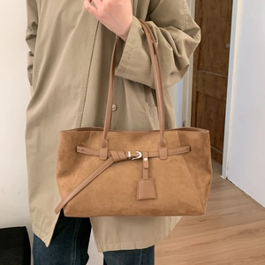Close-up of brown suede tote bag with vintage belt buckle and decorative tag detail