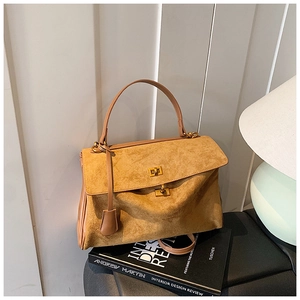 Detail of vintage suede handbag showing brown leather handle and gold twist-lock closure