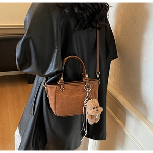 Détail du sac seau à imprimé léopard avec texture en daim et breloque ours en peluche