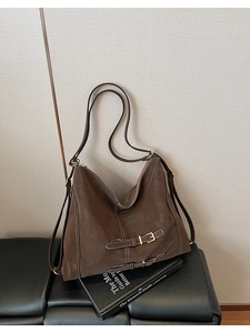 Détail du sac cabas marron vintage montrant les coutures blanches et la boucle décorative