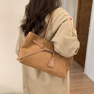 Detail of caramel brown matte suede tote bag with metal buckle and hanging tag