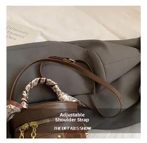 Detail of dark brown cylinder bucket bag with adjustable strap and decorative silk scarf