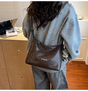 Detail of vintage brown shoulder bag featuring pleated texture and leopard plush charm