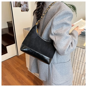 Close-up of a black textured shoulder bag featuring matte suede and glossy leather textures