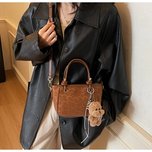 Détail du sac à main vintage léopard avec pendentif ours et bandoulière chic