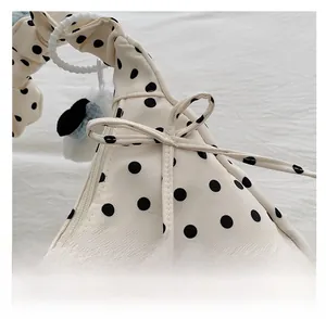 Macro detail of polka dot bag showing zipper closure, bow decor and plush charm