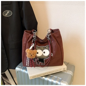 Détail du sac cabas bordeaux avec broderie chat, bandoulière chaîne et charme ours