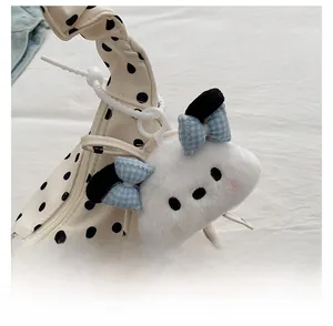 Detail of plush dog keychain with blue bows on a white polka dot pleated bag