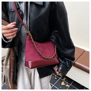 Detail view of burgundy leather tote bag with gold chain and suede texture on model
