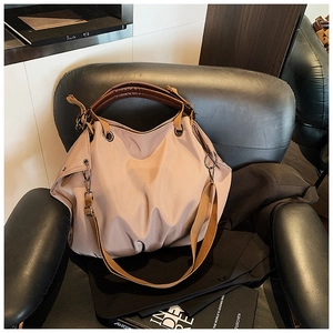 Close-up of beige canvas tote bag with brown leather handles on black chair