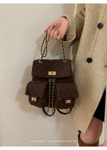 Detail of retro dark brown quilted suede backpack with golden chain straps and turn-lock