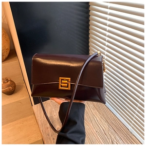 Detail of a vintage dark brown leather shoulder bag featuring a gold square metal buckle